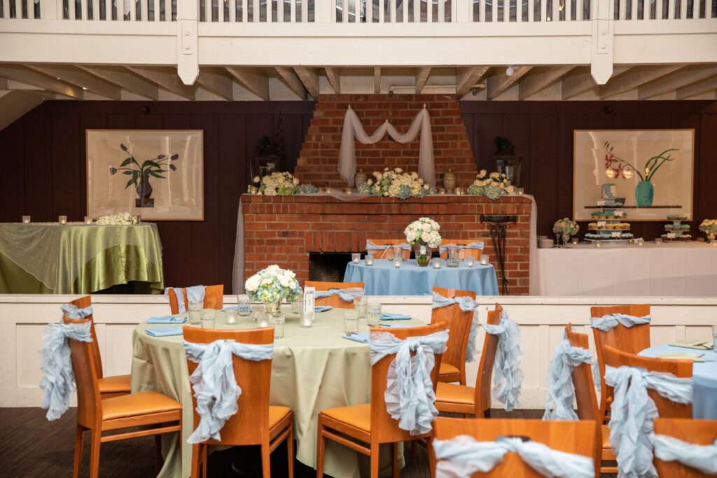 Wedding reception room with sage linens and blue chair sashes